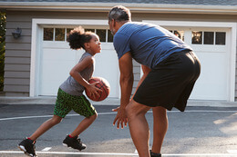 Father And Daughter Playing Basketball In Front Yard
